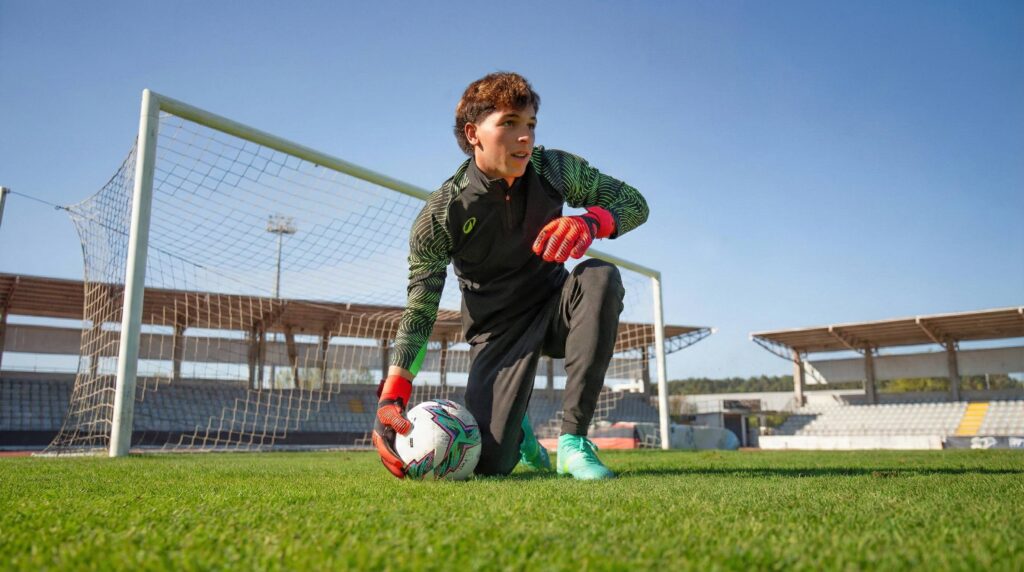 Goalkeeper wearing a custom goalkeeper kit while training on a football pitch in front of the goal
