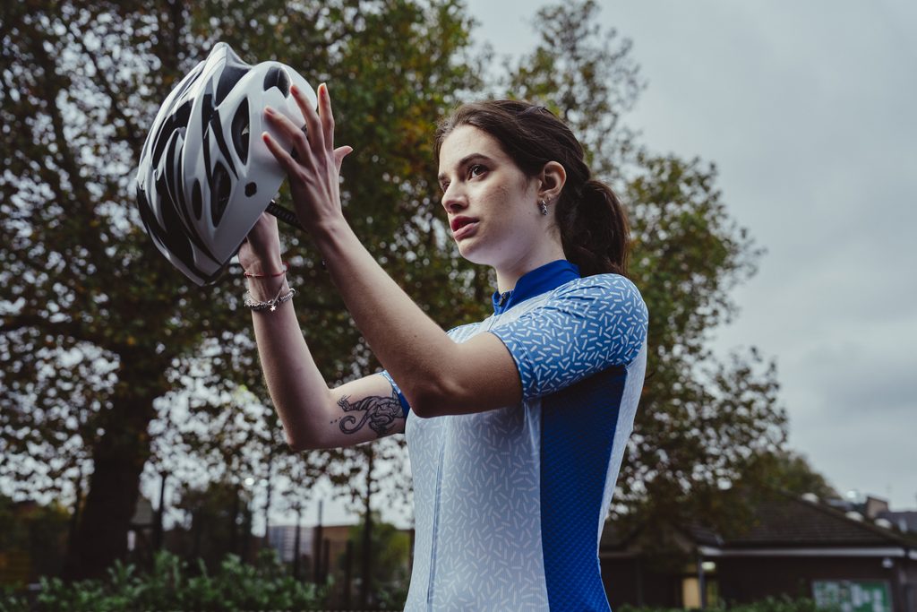 Female cyclist putting helmet on wearing Decathlon Club custom cycling jersey.